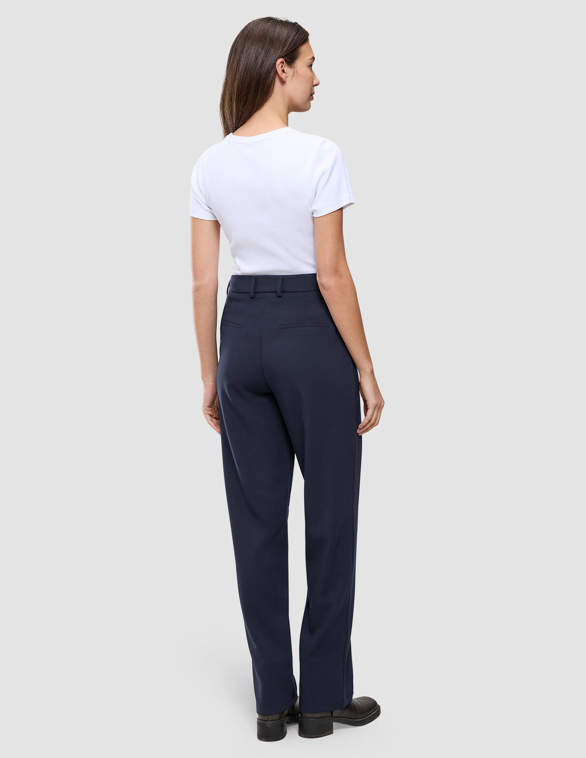 En kvinna bär en vit t-shirt och byxorna Women GO2 Pants Straight Blue Nights, som har raka ben och en skandinavisk design.