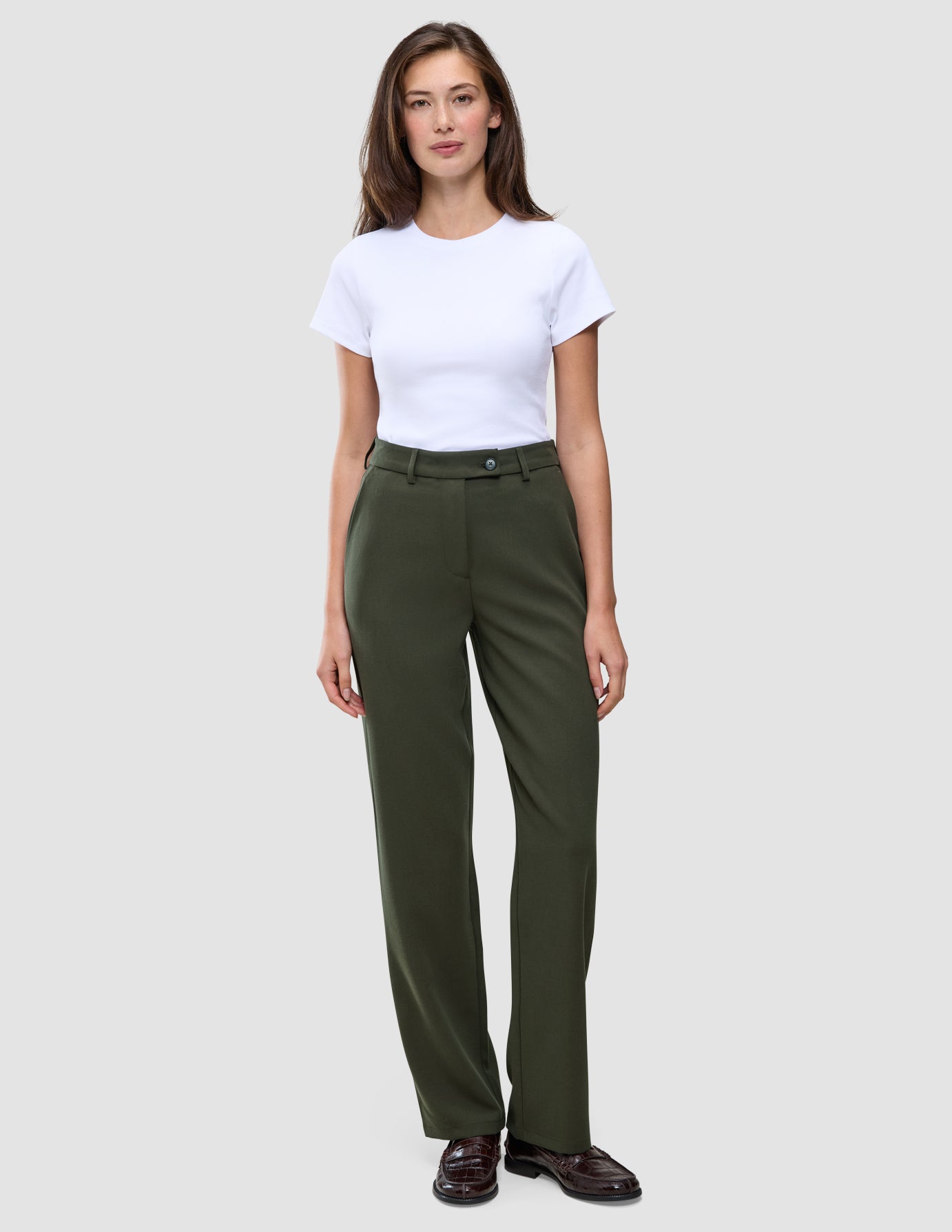 En person som bär en vit t-shirt och ett par Women GO2-byxor i färgen Dusty Olive med raka ben.