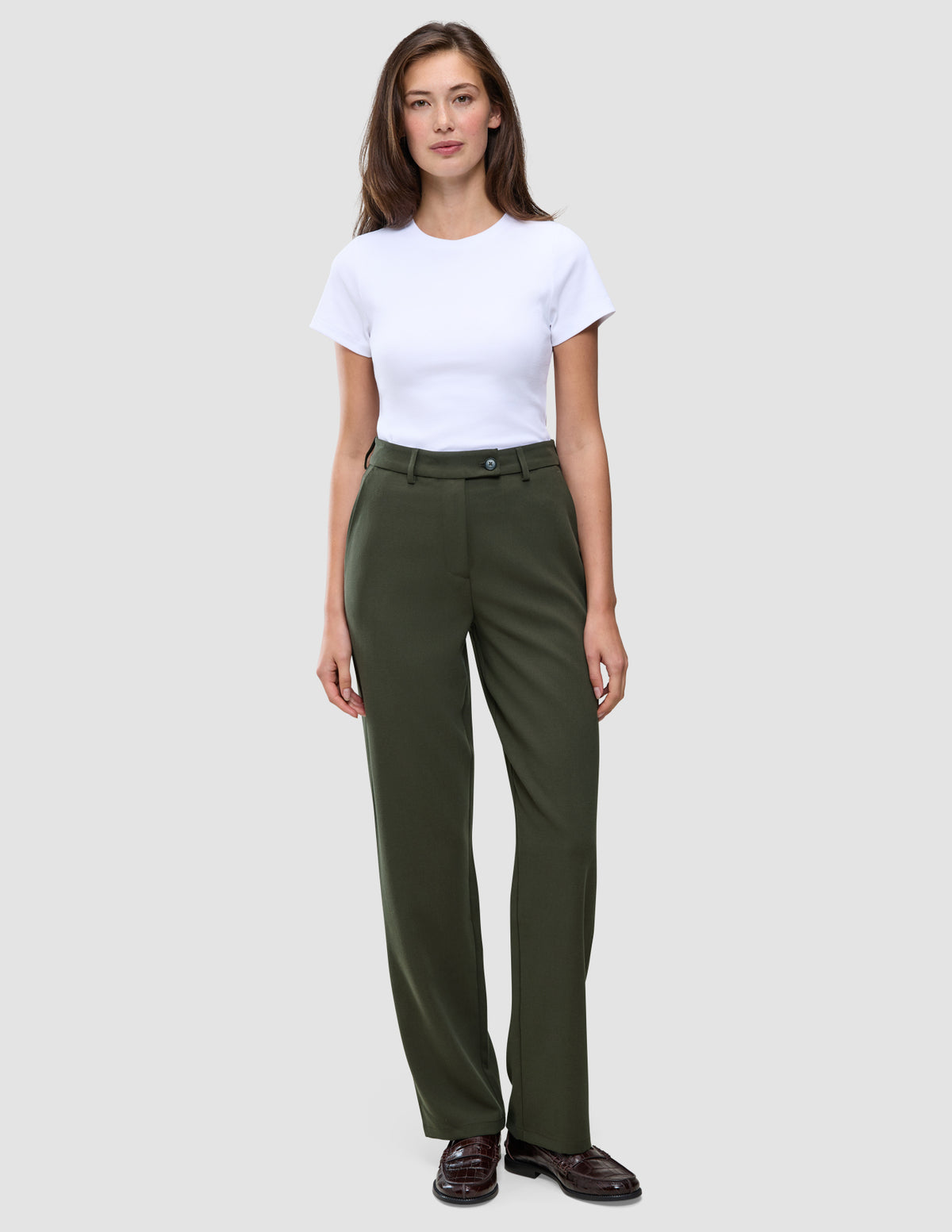 En person som bär en vit t-shirt och ett par Women GO2-byxor i färgen Dusty Olive med raka ben.