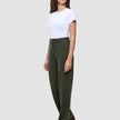 En kvinna bär en vit t-shirt instoppad i ett par högmidjade Women GO2 Pants Straight i färgen Dusty Olive samt mörka loafers.