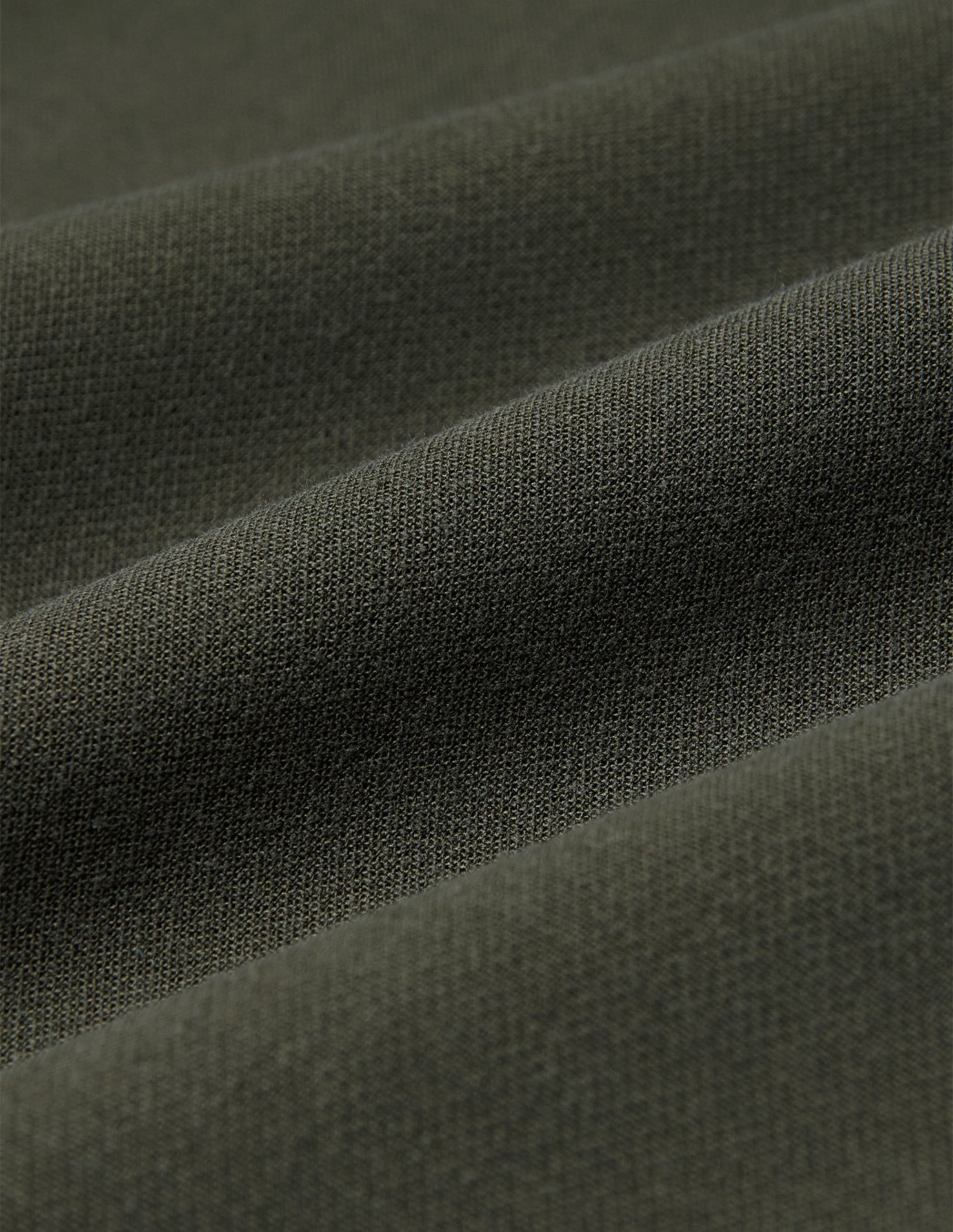 Närbild på olivgröna GO2-byxor för damer i rakt snitt, i tyget Dusty Olive med mjuka veck, som präglas av en minimalistisk design.