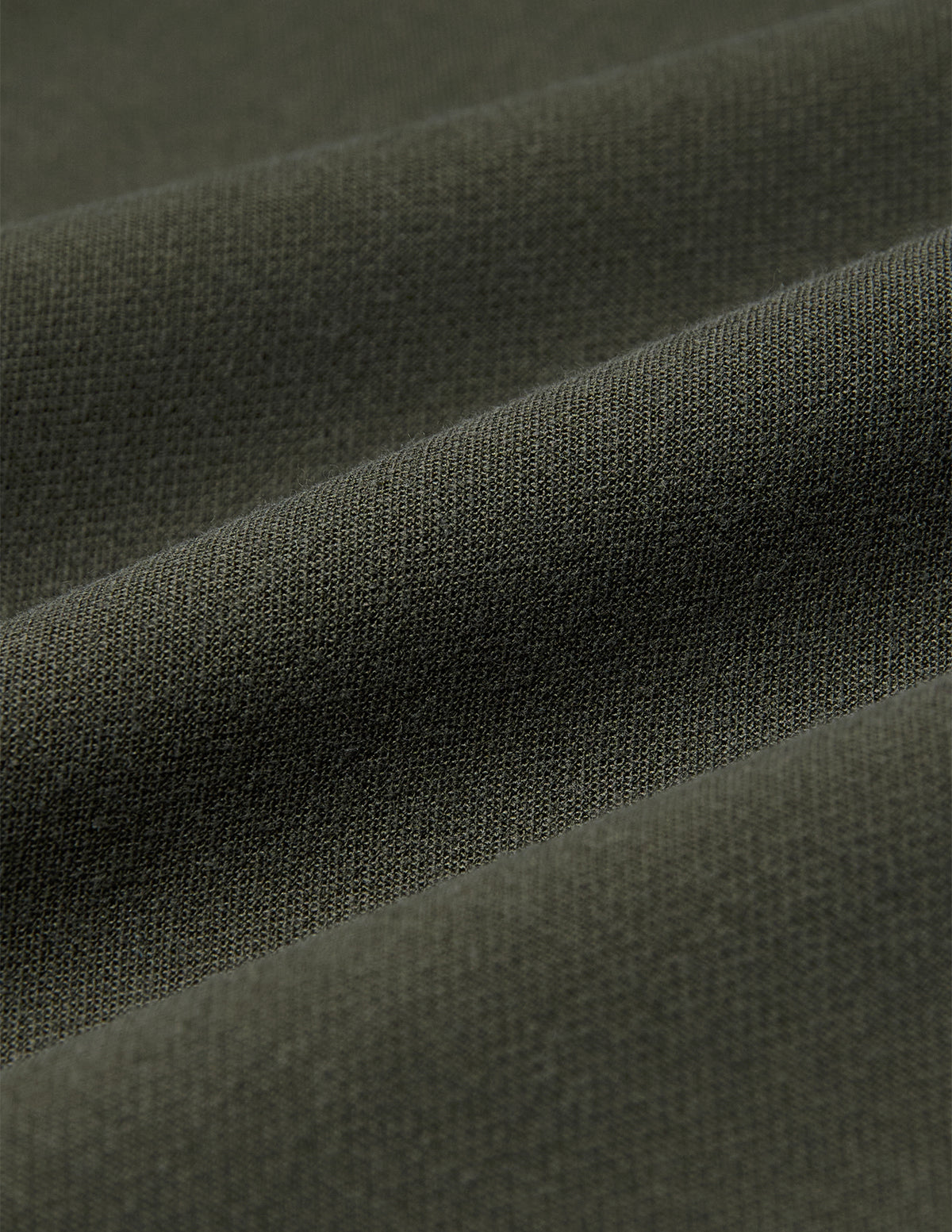 Närbild på olivgröna GO2-byxor för damer i rakt snitt, i tyget Dusty Olive med mjuka veck, som präglas av en minimalistisk design.
