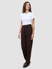 En kvinna bär en vit t-shirt och byxor av modellen Women GO2 Pants Straight Mocha i en rak, brun modell, tillsammans med mörka loafers.