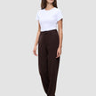 En kvinna bär en vit t-shirt och byxor av modellen Women GO2 Pants Straight Mocha i en rak, brun modell, tillsammans med mörka loafers.