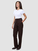 En kvinna klädd i en vit t-shirt och ett par Women GO2 Pants Straight Mocha med raka ben, med handen i fickan.