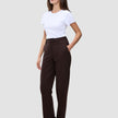 En kvinna klädd i en vit t-shirt och ett par Women GO2 Pants Straight Mocha med raka ben, med handen i fickan.