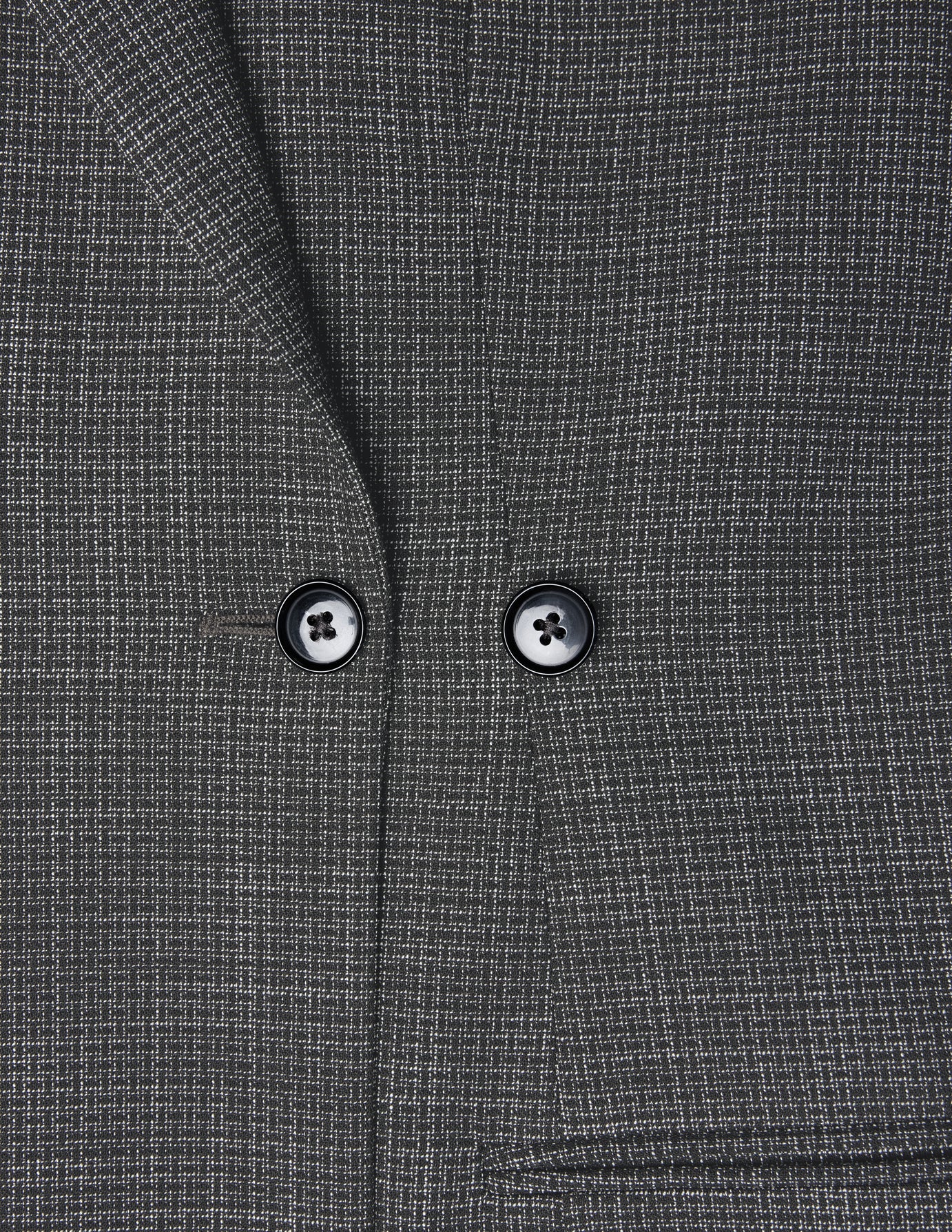 Närbild på Women Nara Blazer Fitted Black Check, en mörkgrå kavaj med ett diskret vitt rutmönster och två svarta knappar.