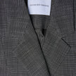Närbild på en svartvit rutig damblazer av modellen Nara Blazer Fitted Black Check med en etikett i nacken med texten SHAPING NEW TOMORROW.