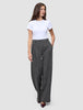 Kvinna klädd i en vit t-shirt och byxor av modellen Nara Pants Wide Black Check med ett diskret mönster.