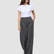 Kvinna klädd i en vit t-shirt och byxor av modellen Nara Pants Wide Black Check med ett diskret mönster.