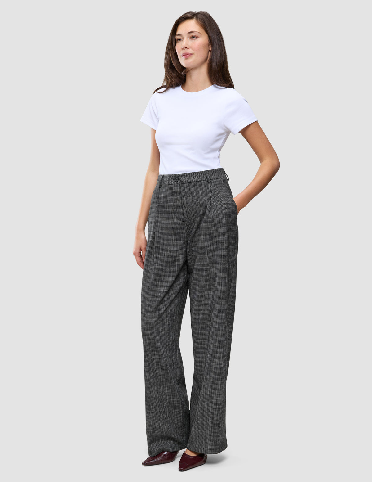 En person klädd i en vit t-shirt och ett par Women Nara Pants Wide Black Check med mörkgrått rutmönster.