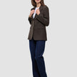En kvinna klädd i en Women Serene Blazer Regular Walnut Herringbone, en vit t-shirt och mörkblå jeans.