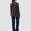 Bakifrånbild av en person klädd i en Women Serene Blazer Regular Walnut Herringbone, mörkblå jeans och bruna skor med ullfinish.