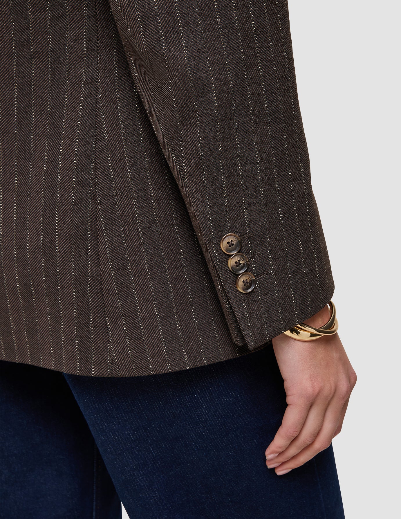 Närbild på en brun Women Serene Blazer Regular Walnut Herringbone-kavaj med tre knappar och ett guldarmband.