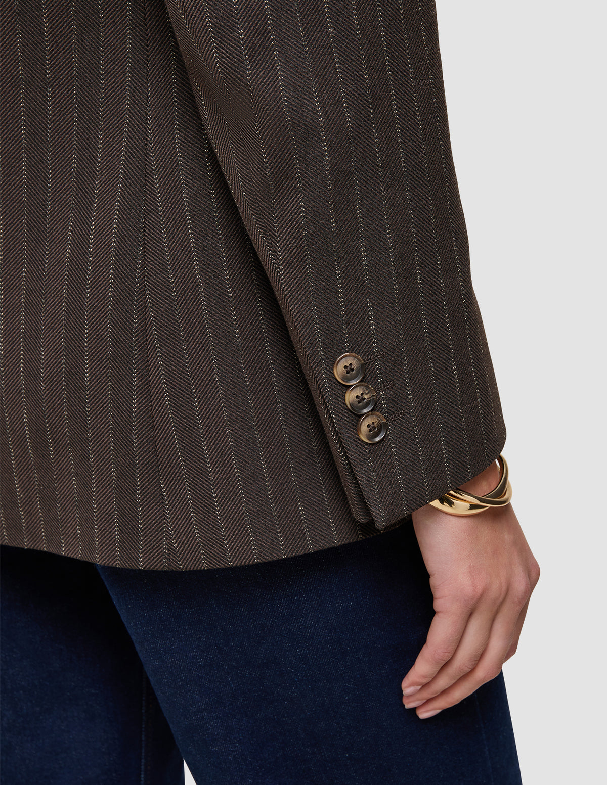 Närbild på en brun Women Serene Blazer Regular Walnut Herringbone-kavaj med tre knappar och ett guldarmband.