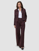 En kvinna bär en vinröd blazer med smala ränder och byxorna Women Serene Pants Wide Berry Pinstripe över en vit skjorta med krage.