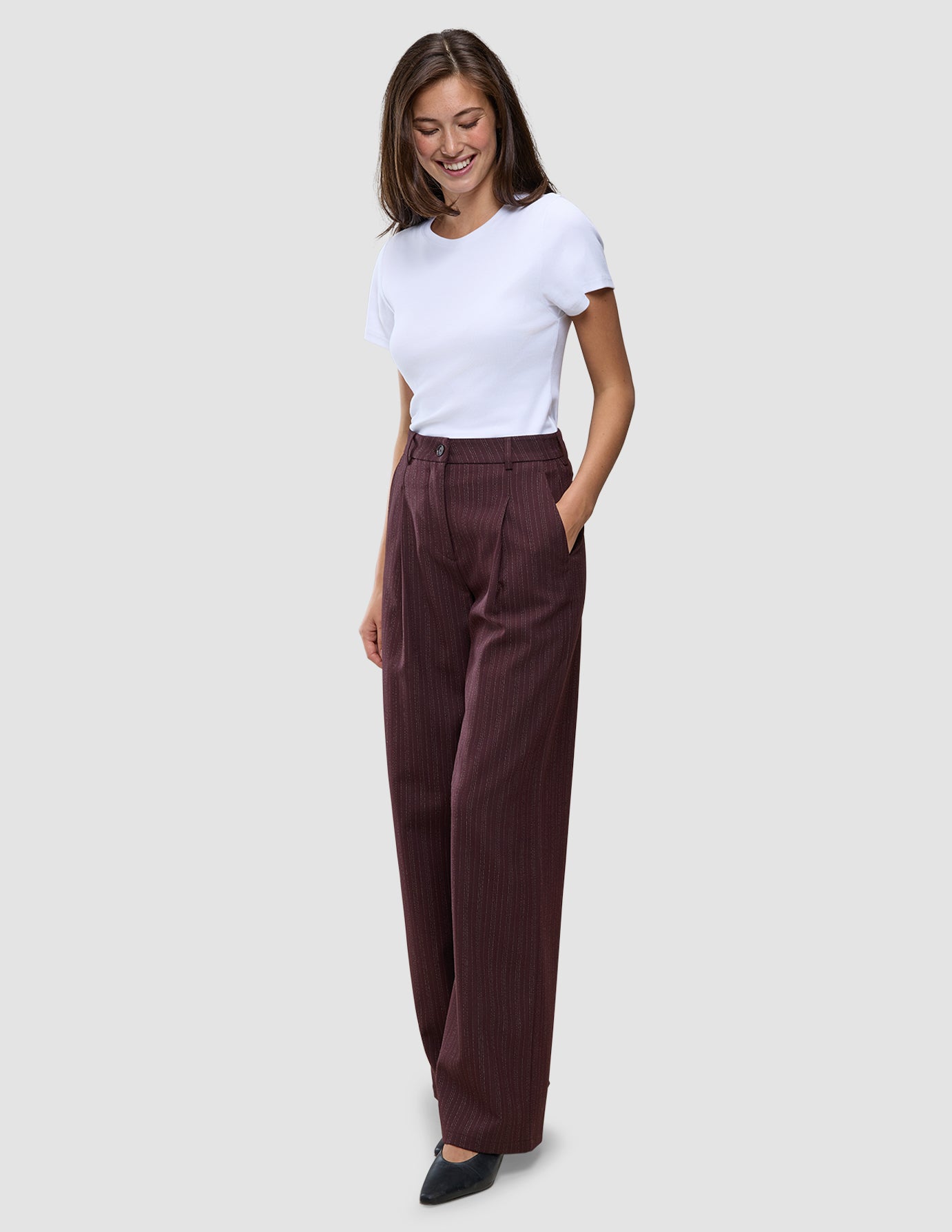 En kvinna i en vit t-shirt och byxor av modellen Women Serene Pants Wide Berry Pinstripe.