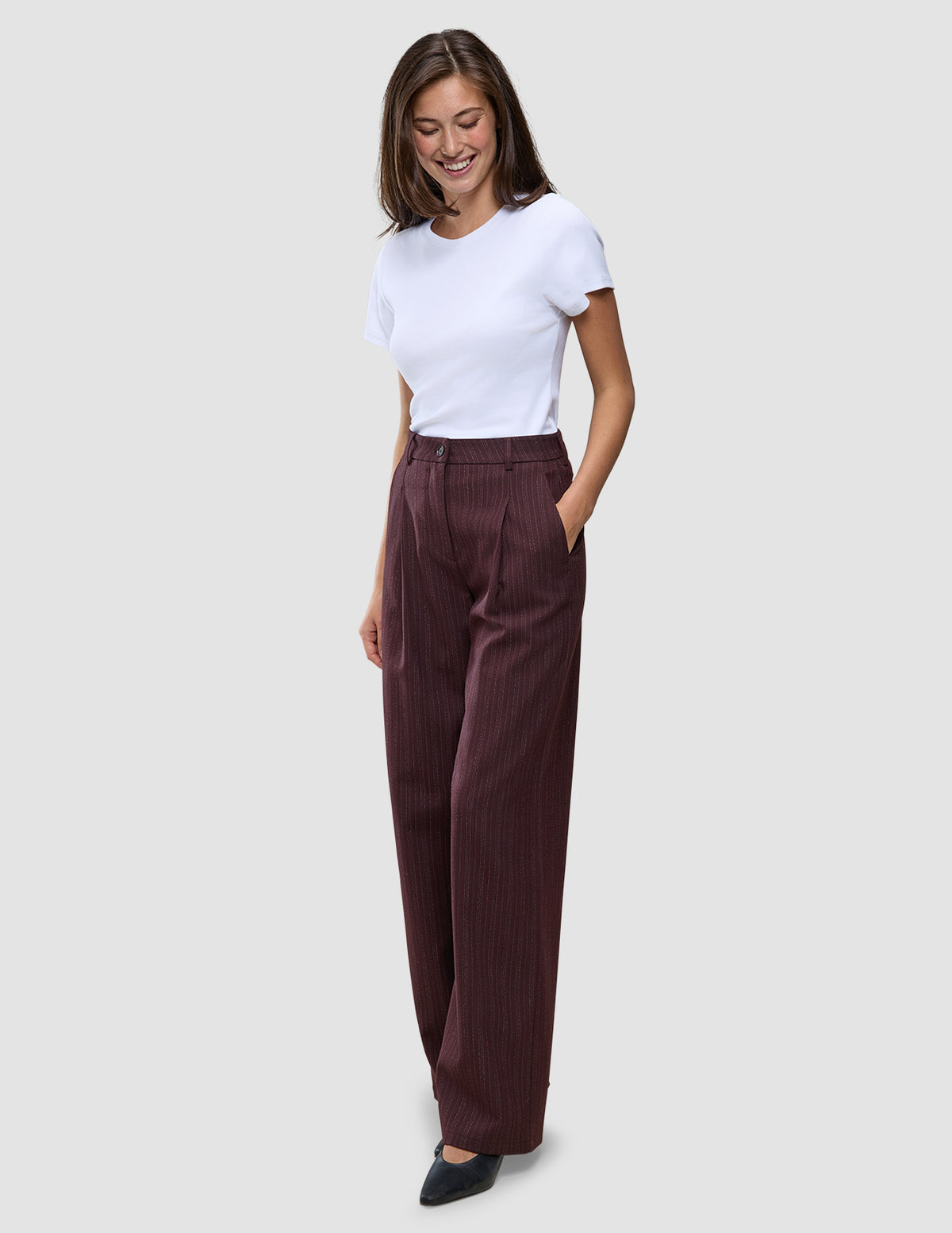 En kvinna i en vit t-shirt och byxor av modellen Women Serene Pants Wide Berry Pinstripe.
