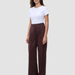 En person i en vit t-shirt och byxorna Women Serene Pants Wide Berry Pinstripe i mörkrött tyg med smala ränder.