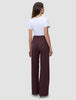 En person klädd i en vit t-shirt och byxorna Women Serene Pants Wide Berry Pinstripe med vid benvidd och ett mörkt bärfärgat mönster.