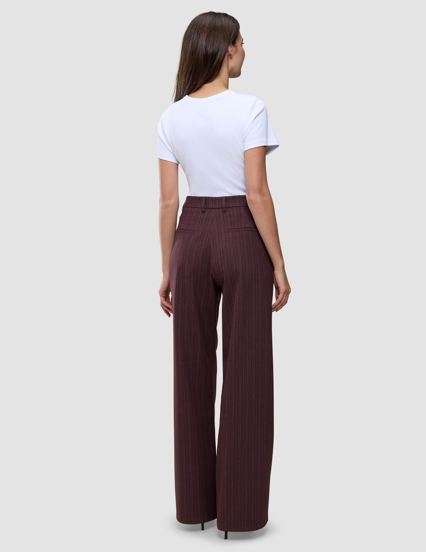 En person klädd i en vit t-shirt och byxorna Women Serene Pants Wide Berry Pinstripe med vid benvidd och ett mörkt bärfärgat mönster.