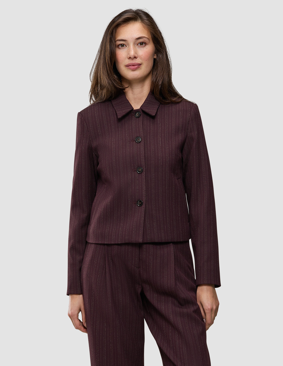 En kvinna bär en Women Serene Short Jacket Berry Pinstripe med bärfärgade smala ränder i ullliknande material och krage.