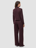 En kvinna sedd bakifrån, klädd i en kort jacka av modellen Women Serene Short Jacket Berry Pinstripe och matchande byxor med vida ben.
