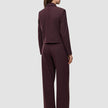 En kvinna sedd bakifrån, klädd i en kort jacka av modellen Women Serene Short Jacket Berry Pinstripe och matchande byxor med vida ben.