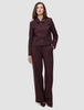 En person bär den korta damjackan Serene i färgen Berry Pinstripe tillsammans med matchande byxor med vida ben i minimalistisk design.